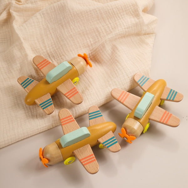 Three wooden toy airplanes with colorful stripes on a beige fabric background