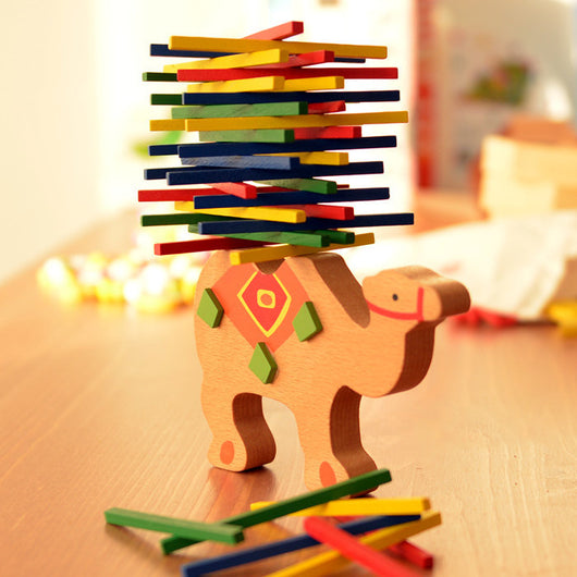 Wooden camel toy with colorful balance beam on a wooden surface