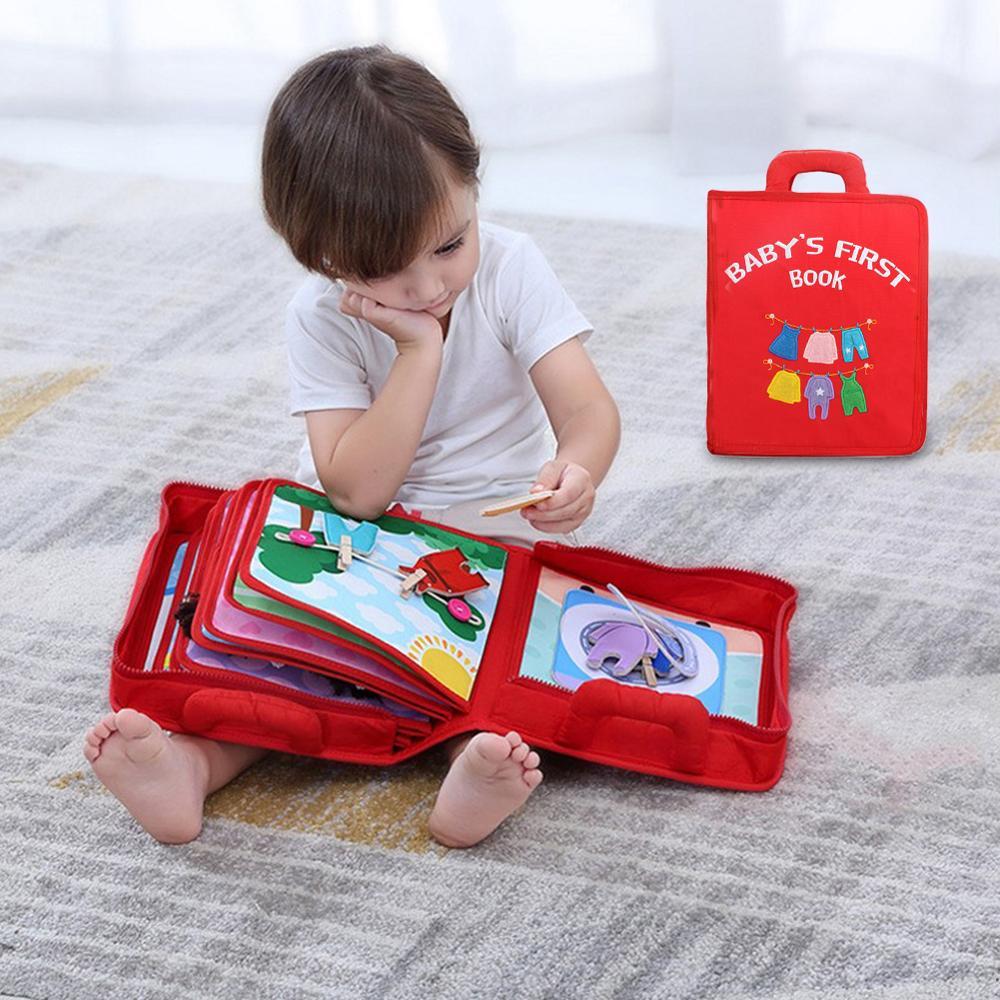 Child playing with a red 'Baby's First Book' on a carpeted floor.