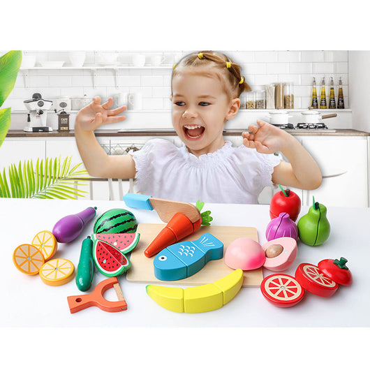 Child playing with colorful toy fruits and vegetables on a kitchen counter.