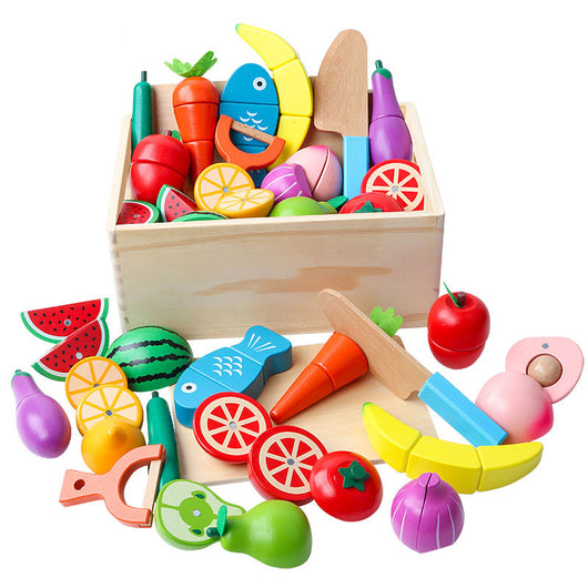 Colorful wooden toy fruits, vegetables, and kitchen items in a wooden box on a white background