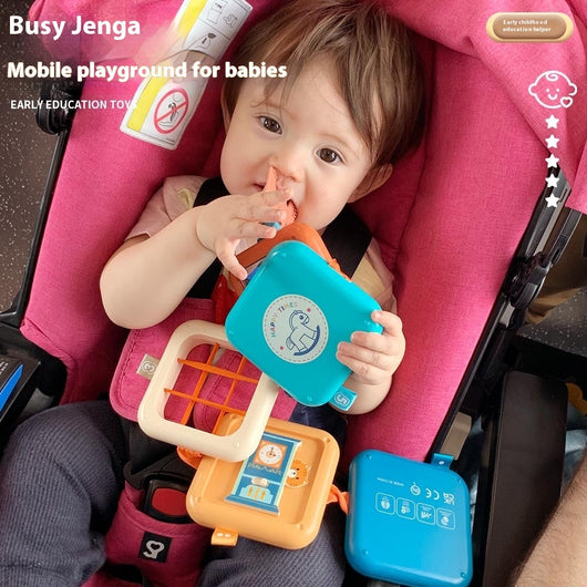 A child sitting in a high chair playing with a colorful Jenga-like puzzle toy made of plastic.