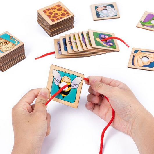Wooden puzzle with colorful illustrations and a red string, held by hands on a white background.