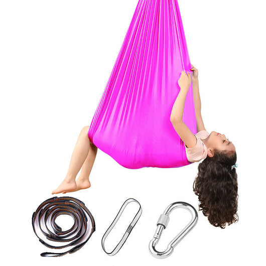 Pink aerial yoga hammock with a child using it, accompanied by a strap and carabiner on a white background.
