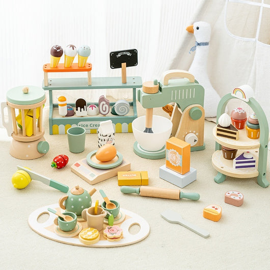 Collection of wooden toys including a tea set, kitchen items, and a ice cream stand on a light surface.