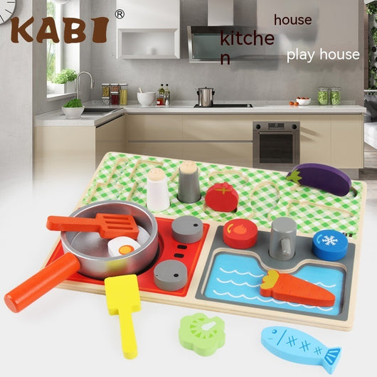 Children's play kitchen set with toy cookware on a table in front of a real kitchen.
