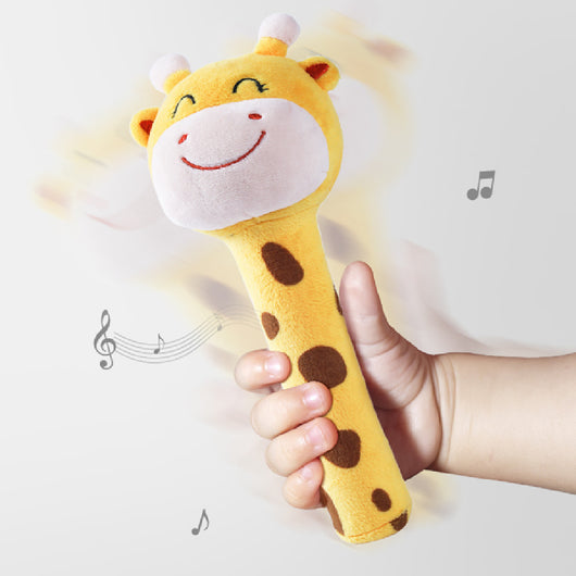 Child's hand holding a giraffe-shaped rattles with music notes indicating sound.