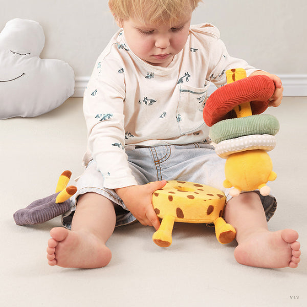Child playing with colorful plush toys on a light-colored floor.