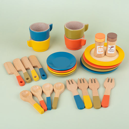 Colorful toy kitchen set with cups, plates, spoons, and forks on a light green background