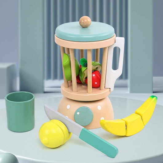 Children's toy kitchen set with a fruit grinder, fruits, and a knife on a light blue surface.