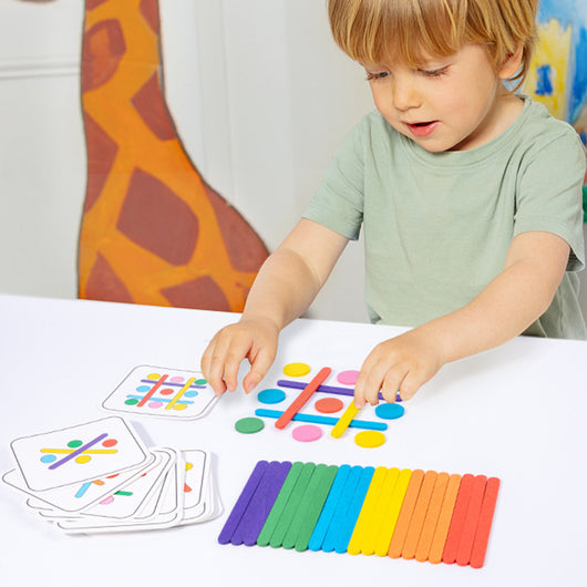 A child playing with colorful wooden sticks arranged in a pattern puzzle on a table.