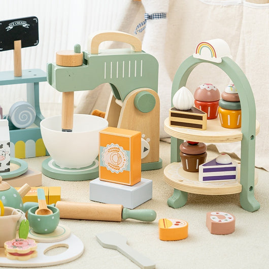 Wooden toy kitchen set with various utensils and a rainbow stand on a light background